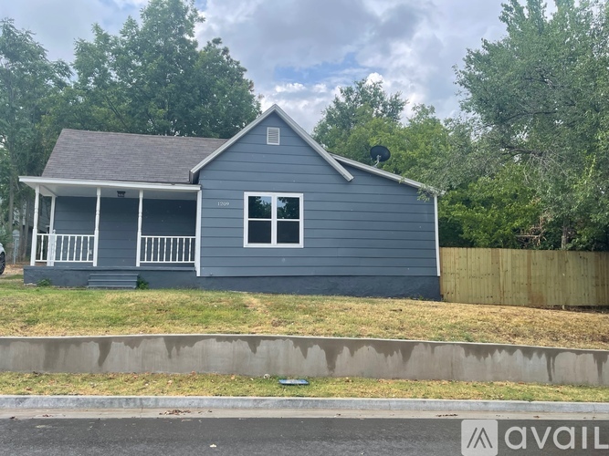 A blue house with a white porch and a satellite dish on the roof.