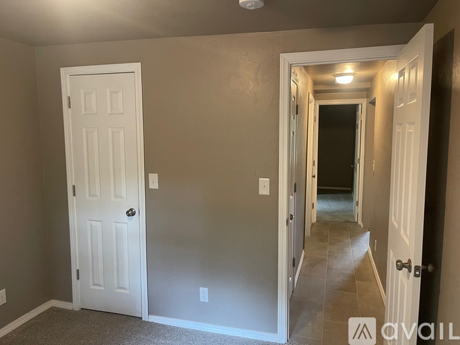 A hallway with a white door on the left and a white door on the right.