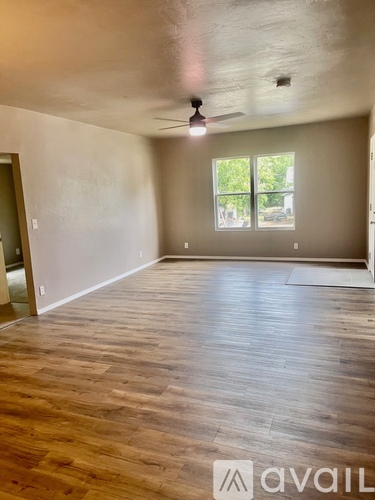 A room with wooden flooring and a window with a view of trees outside.