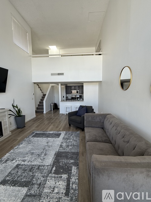 A living room with a grey couch and a wooden floor.