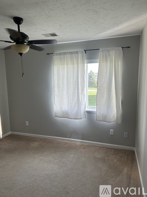 A room with a ceiling fan and carpeted floor.