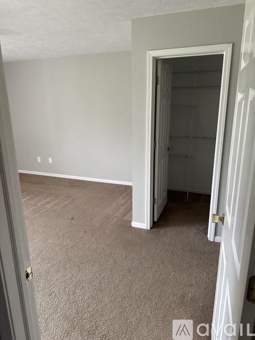 A room with a carpeted floor and a door leading to another room.