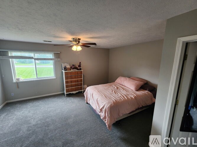 A room with a ceiling fan and carpeted floor.