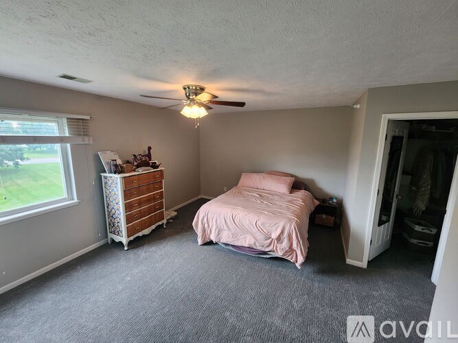 A bedroom with a bed, dresser, and window.