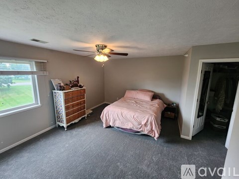 A bedroom with a bed, dresser, and window.