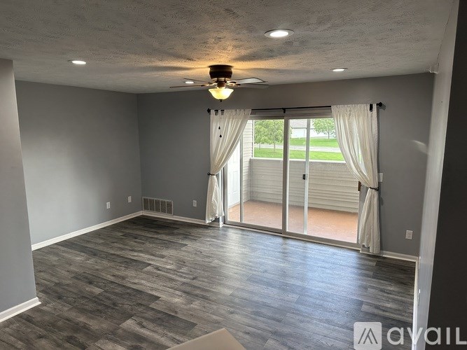 A room with a ceiling fan and sliding glass doors.