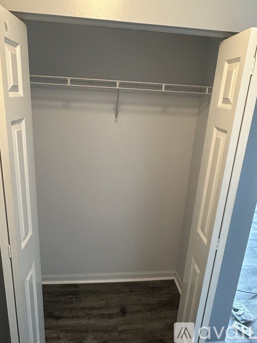 A white closet with a grey shelf and a white door.