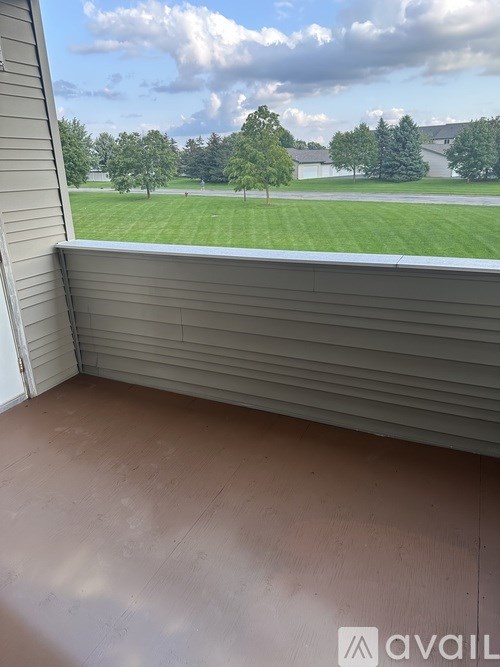 A room with a view of a green lawn and trees.