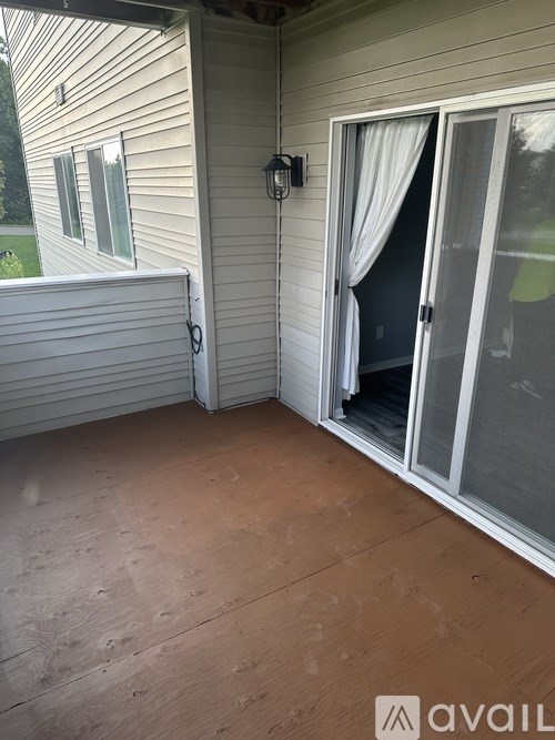 A patio with a sliding glass door and a white curtain.