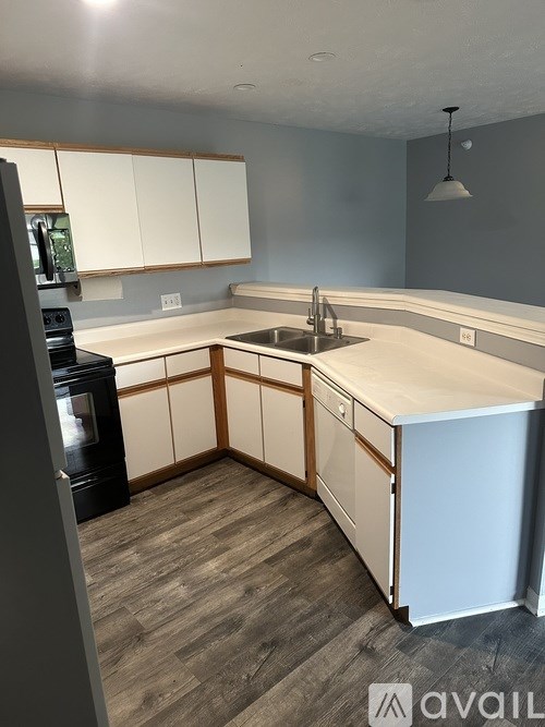 A kitchen with a sink, cabinets, and a refrigerator.
