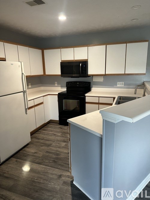 A kitchen with white cabinets and a white refrigerator.
