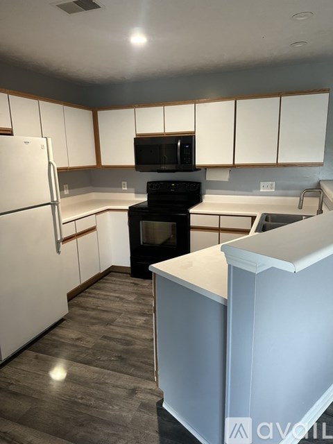 A kitchen with white cabinets and a white refrigerator.