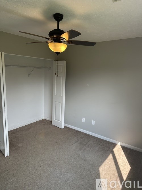 A room with a ceiling fan and carpeted floor.