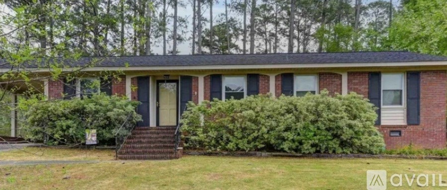 A red brick house with a green bush in front.