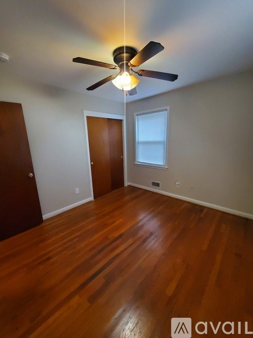 A room with a ceiling fan and wooden flooring.