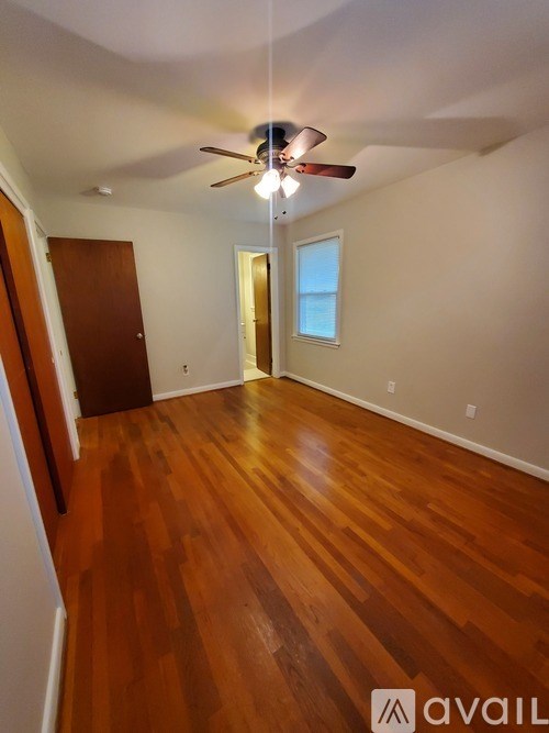 A room with a ceiling fan and wooden flooring.