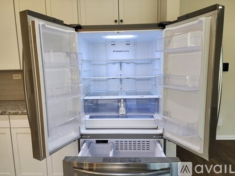 A stainless steel refrigerator with its door open in a kitchen.