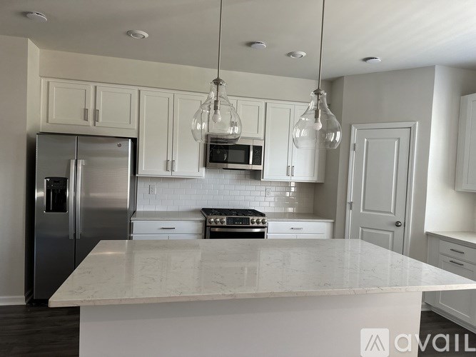 A kitchen with a white marble countertop and stainless steel appliances.