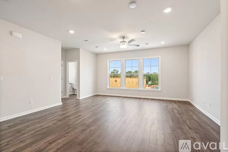 A spacious room with wooden flooring and a ceiling fan.