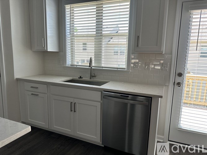 A kitchen with white cabinets and a stainless steel dishwasher.