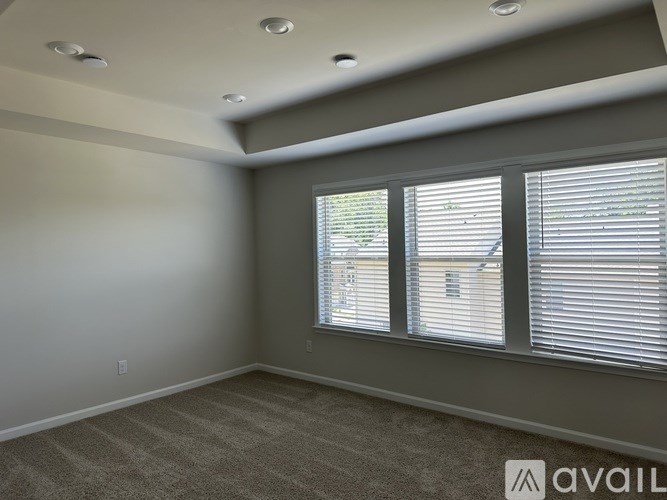 A room with a carpeted floor and a window with blinds.
