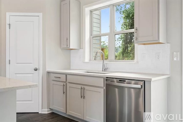 A kitchen with a stainless steel dishwasher and white cabinets.
