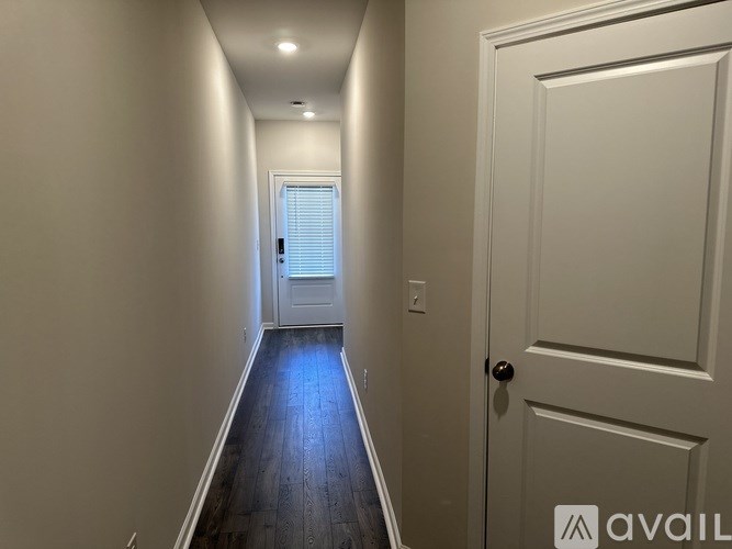 A hallway with a white door and a window with blinds.