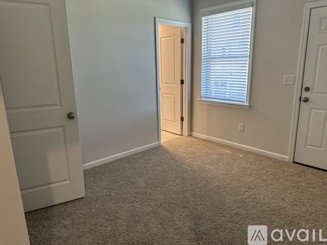 A room with a carpeted floor and a door leading to another room.