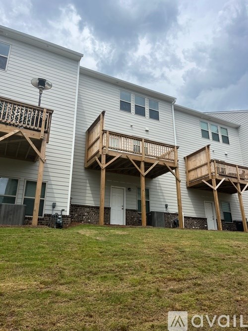 A white building with wooden balconies and a cloudy sky in the background.