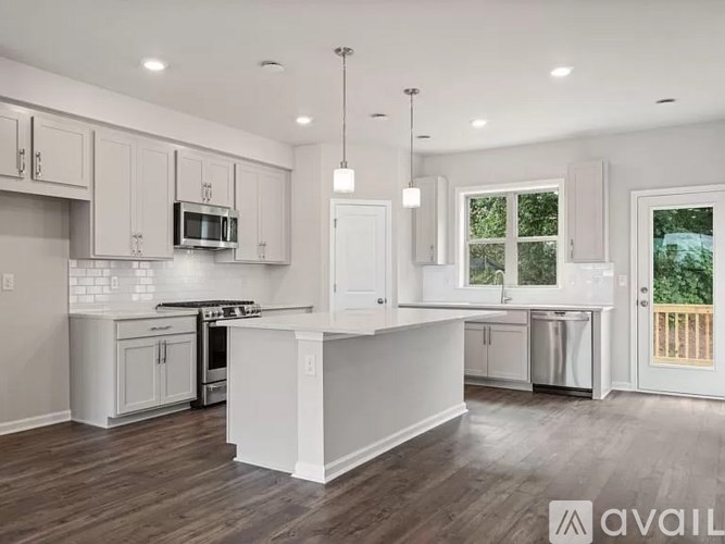 A modern kitchen with white cabinets and a wooden floor.