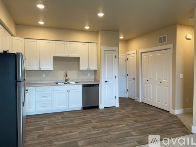 A kitchen with white cabinets and a black refrigerator.