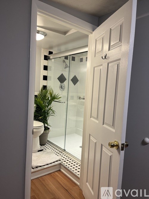 A white door is open to a bathroom with a glass shower.