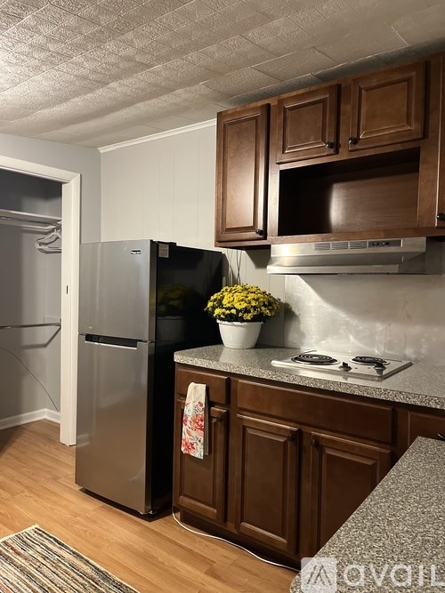 A kitchen with brown cabinets and a black fridge.