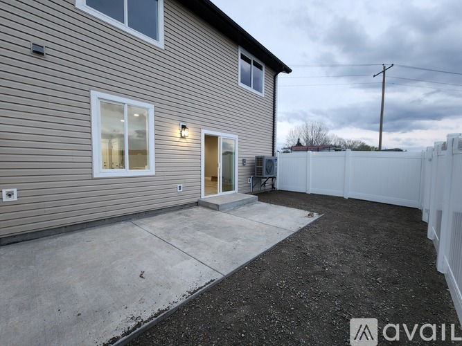 A house with a grey siding and a white fence in the backyard.