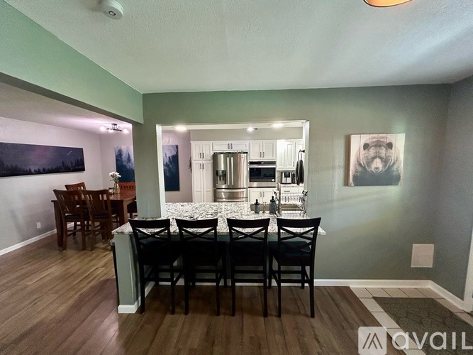 A dining room with a table set for six and a painting of a bear on the wall.