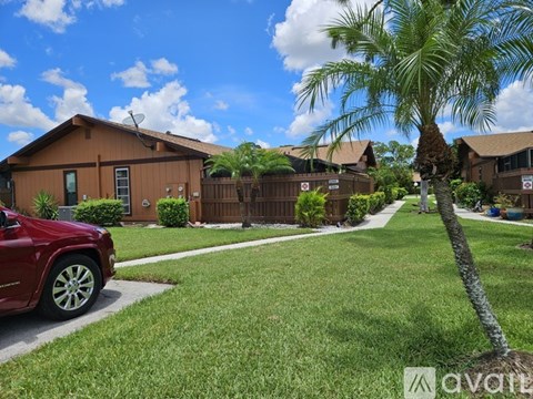 A red car is parked on a driveway in front of a house.