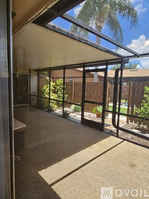 A sunny day in a room with a glass ceiling and a view of the backyard.
