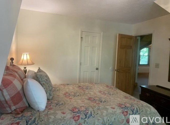 A bedroom with a floral bedspread and a lamp on the side table.