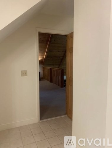 A hallway with a wooden door leading to another room.