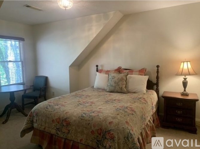 A bedroom with a bed, chair, and lamp.