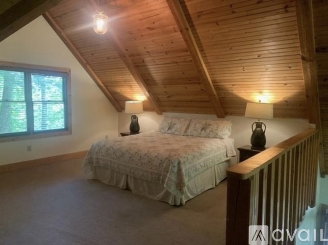 A bedroom with a bed, wooden ceiling, and a window.