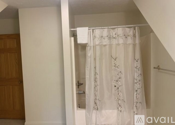 A white curtain with floral designs hangs in a room.