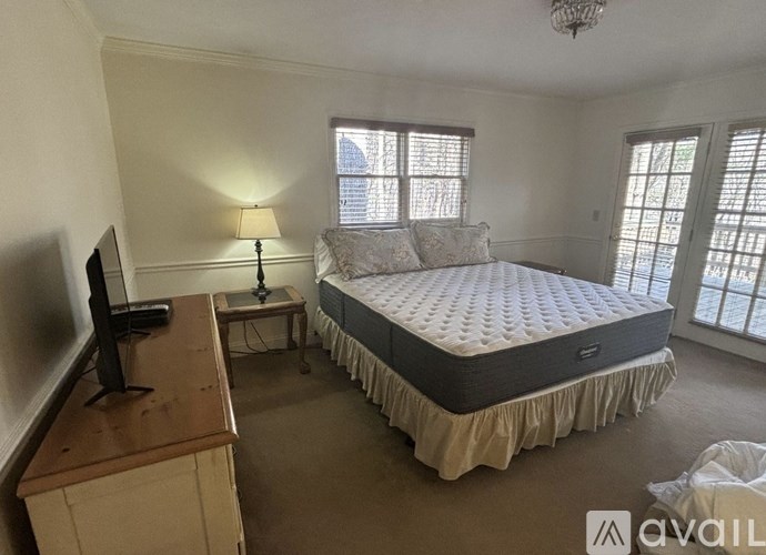 A bedroom with a large bed and a television on a wooden dresser.