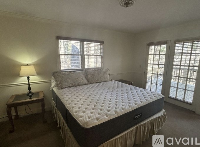 A bedroom with a large bed, a lamp, and a window.