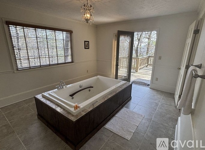 A large bathtub is in a spacious bathroom with a window.