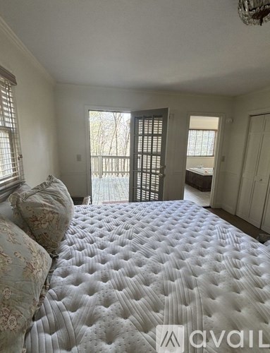 A bedroom with a large bed and a window with blinds.