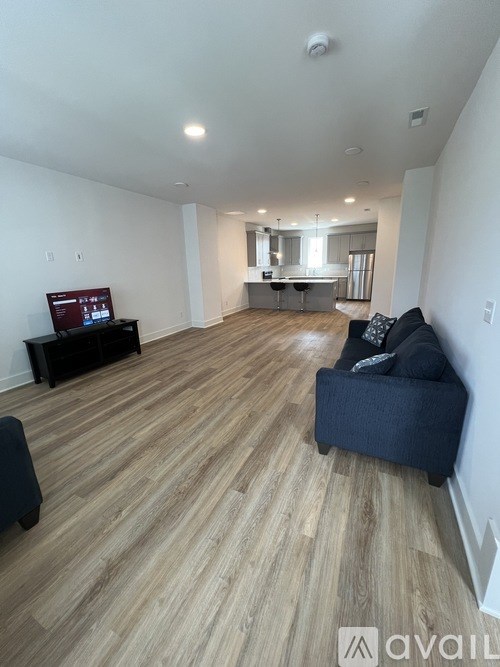 A living room with a black couch and a television on a black stand.