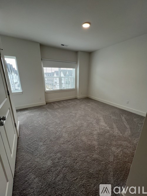 A carpeted room with a window and a door.