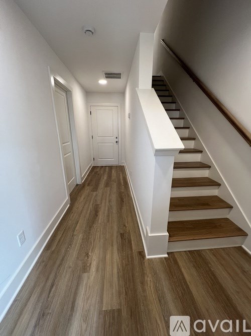 A hallway with wooden floors and a staircase.