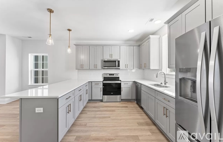 A modern kitchen with stainless steel appliances and wooden floors.